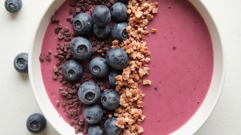 Blueberry smoothie bowl with various toppings.